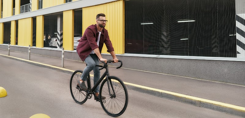 Homme habillé d'un jean et une d'une chemise à carreau qui fait du vélo